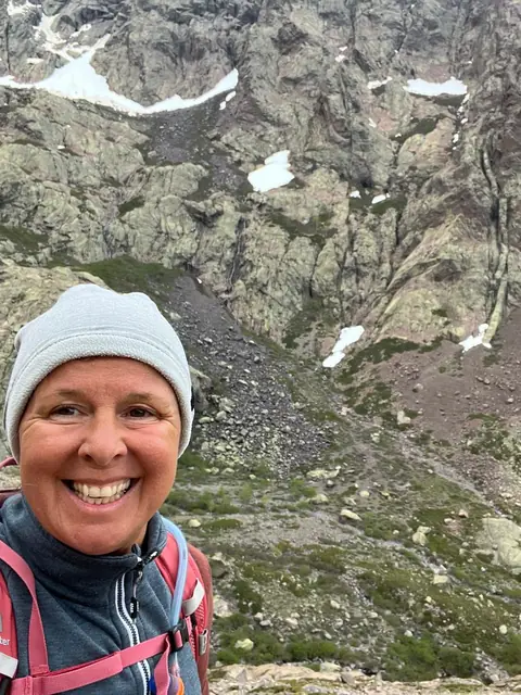 Selfie von Christina mit Mütze vor einer Felswand im Hochgebirge