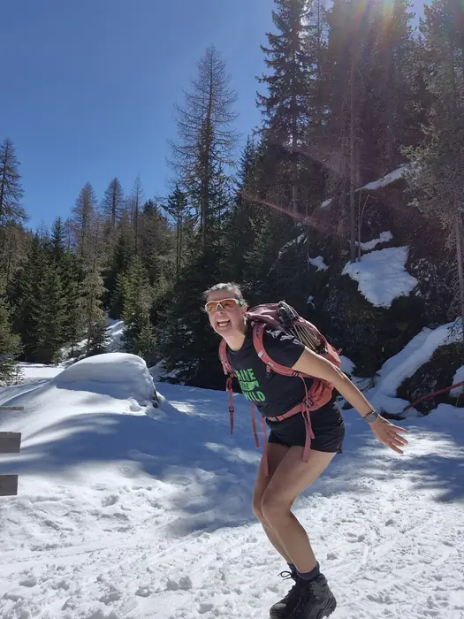 Christina läuft mit Rucksack durch einen verschneiten Bergwald